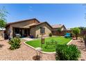 A well-maintained backyard with artificial turf, desert landscaping and covered patio at 7015 W Melody Dr, Laveen, AZ 85339