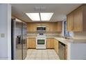 Modern kitchen with stainless steel appliances, light wood cabinets, and tiled countertops at 722 W Topeka Dr, Phoenix, AZ 85027