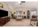 Inviting living room featuring vaulted ceilings, with a ceiling fan and view of dining area at 11543 W Sandsnake Ct, Surprise, AZ 85378