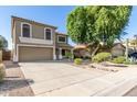 Two-story house with desert landscaping, large shade tree, wide driveway and two-car garage at 16527 W Ironwood St, Surprise, AZ 85388