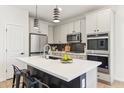 Modern kitchen with white cabinets, a black backsplash, stainless appliances and an island with barstool seating at 6641 N Desert Shadow Ln, Phoenix, AZ 85014