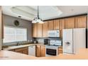 Efficient kitchen with wooden cabinets, white appliances, and natural light at 8245 E Bell Rd # 103, Scottsdale, AZ 85260