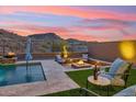 Backyard oasis with a pool, fire pit, and desert landscape creating a relaxing retreat at 16417 W Fawn Dr, Goodyear, AZ 85338