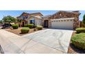 Concrete driveway leads to a two-car garage, with a well-manicured front yard featuring gravel and trimmed bushes at 18041 W Ivy Ln, Surprise, AZ 85388