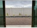 View of a low maintenance backyard with decorative rock and retaining walls through sliding glass doors at 20346 W Sells Dr, Buckeye, AZ 85396
