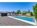 Backyard featuring a pool, covered patio, gravel area, and synthetic grass at 2336 E Flower St, Phoenix, AZ 85016
