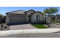 Inviting one-story home boasting lush landscaping, a brick-paved driveway, and a covered entrance, creating curb appeal at 24146 N 162Nd Ln, Surprise, AZ 85387