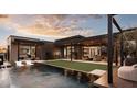 Luxury backyard featuring a pool, grass area, and covered patio perfect for relaxation and entertaining at dusk at 24651 N 127Th Way # 30, Scottsdale, AZ 85255