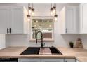 Close up of kitchen sink with modern matte black faucet, butcher block countertops, and subway tile backsplash at 39 N Maple St, Mesa, AZ 85205