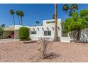Home featuring light-colored walls, desert landscaping, and palm trees in a sunny setting at 4950 N 78Th St, Scottsdale, AZ 85251