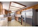 Functional kitchen with stainless steel refrigerator, traditional wood cabinets, and a peek to the living room at 501 E Hill Dr, Avondale, AZ 85323