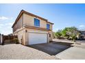 View of the two-story home featuring a two-car garage, desert landscaping, and a front brick patio at 5401 N 104Th Dr, Glendale, AZ 85307