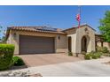 Charming single-story home featuring an arched entryway, desert landscaping, an American flag, a tile roof, and a two car garage at 10310 E Tillman Ave, Mesa, AZ 85212