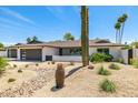 Charming single-story home featuring a three-car garage, modern curb appeal, and desert landscaping with a cactus at 13601 N 50Th Pl, Scottsdale, AZ 85254