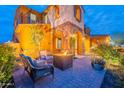 Outdoor patio with stone arches, a fire pit, and comfortable seating under warm, inviting lighting at 27809 N Silverado Ranch Rd, Peoria, AZ 85383