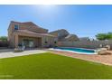 An expansive backyard featuring lush artificial turf, a sparkling pool, and a covered patio at 3113 N 303Rd Dr, Buckeye, AZ 85396