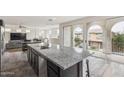 Open kitchen with granite countertops, black cabinets, and an island, all illuminated by sliding glass doors to a balcony at 4353 E Erie St, Gilbert, AZ 85295