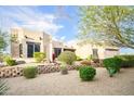 Beige stucco home with desert landscaping featuring gravel, greenery and a retaining wall at 5520 E Desert Forest Trl, Cave Creek, AZ 85331