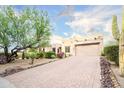 View of the beige stucco home with a paver driveway, desert plants and a Saguaro cactus at 5520 E Desert Forest Trl, Cave Creek, AZ 85331