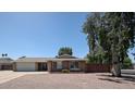 Charming single-story brick home featuring a lush front yard, mature trees and a two-car garage at 759 W Los Lagos Vista Ave, Mesa, AZ 85210