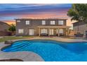 A spacious backyard with a sparkling blue pool, covered patio, and green lawn at 7129 S Stadium Way, Gilbert, AZ 85298