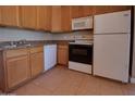 Functional kitchen with wood cabinets, white appliances, and tile flooring at 7930 E Broadway Rd, Mesa, AZ 85208
