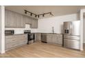 Open kitchen with stainless steel appliances, modern gray cabinets, and laminate floors at 12424 N B St, El Mirage, AZ 85335