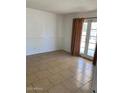 A bright, airy bedroom with tile flooring, neutral walls, and access to the backyard through glass patio doors at 13208 N 51St Ln, Glendale, AZ 85304