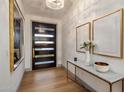 Elegant entryway featuring wood floors, modern light fixture, console table with art, and a stylish front door at 3626 N Mohave Way, Scottsdale, AZ 85251