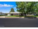A charming single-story home with a well-kept lawn, mature trees, and a covered carport at 4510 E Calle Tuberia --, Phoenix, AZ 85018