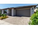 View of the garage, brick driveway, and well maintained landscaping of this stylish home at 9312 E Spiral Ave, Mesa, AZ 85212