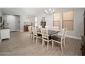 Elegant dining room featuring a modern chandelier, large windows, and a long table with seating for eight at 18401 W Westfall Way, Surprise, AZ 85374