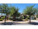 Attractive single-level home featuring a stone facade, desert landscaping, and mature trees at 21985 E Quintero Rd, Queen Creek, AZ 85142