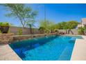 Beautiful pool with waterfall feature, complemented by lush landscaping, and outdoor seating area at 22304 N 104Th Ln, Peoria, AZ 85383