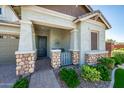 Inviting front porch showcasing stone accents on columns and a seating area, complemented by lush landscaping at 2611 S Quaintance St, Gilbert, AZ 85295