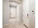 Bright hallway featuring neutral walls, archway, wood-look tile flooring, and a visible alarm system keypad at 2611 S Quaintance St, Gilbert, AZ 85295