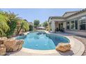 Backyard oasis with pebble tec pool, large rock features, covered patio, mature landscaping, and blue umbrella at 3280 E Coconino Dr, Gilbert, AZ 85298