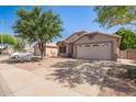 Street view featuring a beige single-story home, well-kept desert landscaping, and a two-car garage at 4911 E Holmes Ave, Mesa, AZ 85206