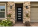 Stunning stone entryway with a modern black door and decorative potted plants at 5515 S Caisson Way, Mesa, AZ 85212