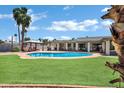 Backyard showcasing a large pool, grass area, covered patio, and desert landscaping at 8936 N 80Th Pl, Scottsdale, AZ 85258