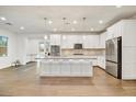 A well-lit kitchen features white cabinets, stainless steel appliances, a center island and wood floors that offer modern elegance at 970 W Zion Way, Chandler, AZ 85248