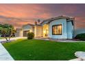 Beautiful one story home with a well-manicured lawn, large windows and a two car garage at sunset at 1312 W Bartlett Way, Chandler, AZ 85248