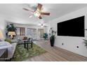 Bright living room with wood floors, ample natural light, ceiling fan, and large TV at 2804 N Nebraska St, Chandler, AZ 85225