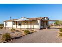 A charming one-story home with a covered front porch and porte-cochere surrounded by desert landscaping at 3349 N Ralston Rd, Maricopa, AZ 85139