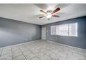 Spacious living room featuring neutral tile flooring, a ceiling fan, and a large window at 3810 N Maryvale Pkwy # 1059, Phoenix, AZ 85031