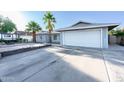 A single-story home with gray siding, palm trees, a brick driveway, and a two-car garage at 4628 W Solano S Dr, Glendale, AZ 85301
