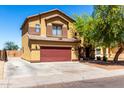 Two-story home with a brick red garage door, desert landscaping, and tan siding at 6320 S 26Th Dr, Phoenix, AZ 85041