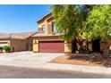Two-story home with a brick red garage door, desert landscaping, and tan siding at 6320 S 26Th Dr, Phoenix, AZ 85041