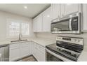 Well-lit kitchen featuring stainless steel appliances, white cabinets, countertops, and modern fixtures at 763 E Maddison St, San Tan Valley, AZ 85140