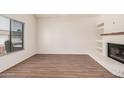 Cozy living room featuring a white-painted brick fireplace, a window and wood-look flooring at 927 E Charleston Ave, Phoenix, AZ 85022